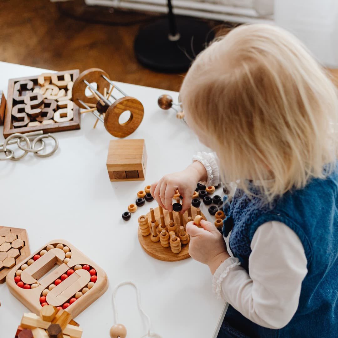 A toddler absorbed in a wooden Montessori stacking and counting activity
